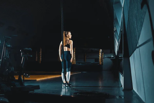 Full length wide angle shot of a woman performing rope climbs at