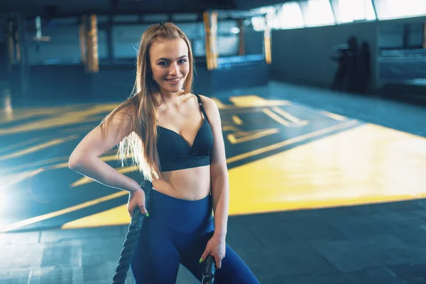 Narrow angle shot of a young woman working out with battle ropes — Stock Photo, Image