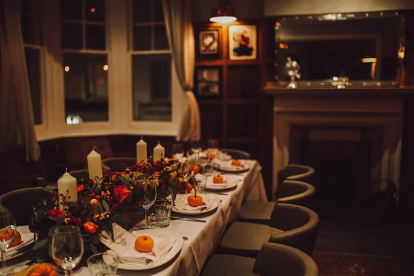 Thanksgiving table setting with automnal decorations, pumpkins, glasses and plates. Holidays, catering and hospitality concept.