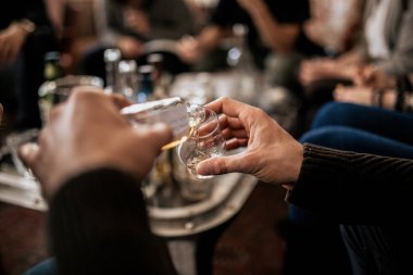 Samlping şişesinden viski döken bir adamın yakın çekimi. İnce alkol kavramı, Japon viskisinin tadımı. Ana sınıf ve degustation.