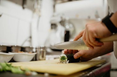 Suşi yapan bir şefin yakın çekimi. Japon kültür mutfağı, yemek ve misafirperverlik kavramı.  