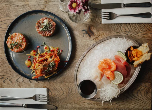 Soya sosu, ton balığı ve havuç salatası ile somon tartar ile sashimi tabağı düz bir atış yatıyordu. Catering, restoran ve çiğ gıda kavramı. Üst görünüm, plakalar üzerinde seçici odak. Tam olarak yemek masası kurmak.