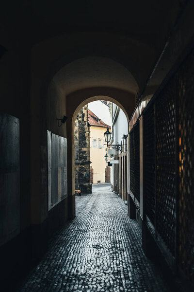 Dark narrow street in the arch in Prague with paving stone