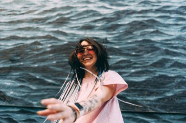 Kadın dövme elleriyle üzerinde arka planda denizle havada saat