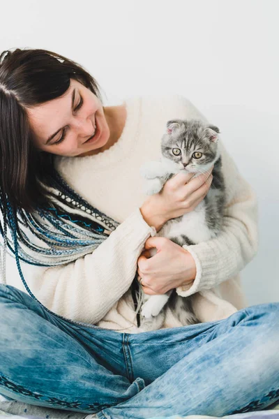 Ona küçük bir kedi yavrusu çok gülümseyen genç dreadlock kızla rahat yatak odasında eller  