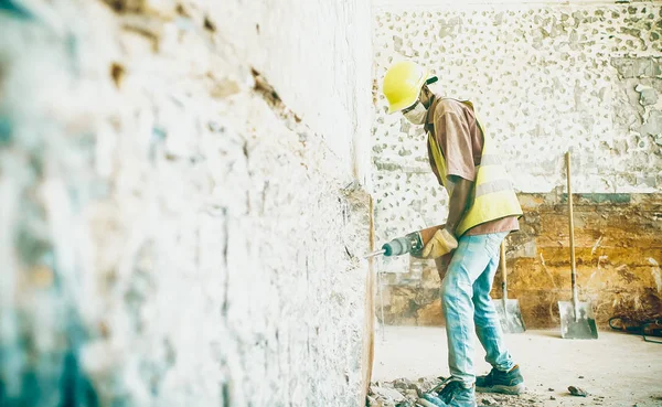 İnşaat alanında pnömatik çekici olan genç bir işçi. İnşaat alanında Afrikalı işçi. 