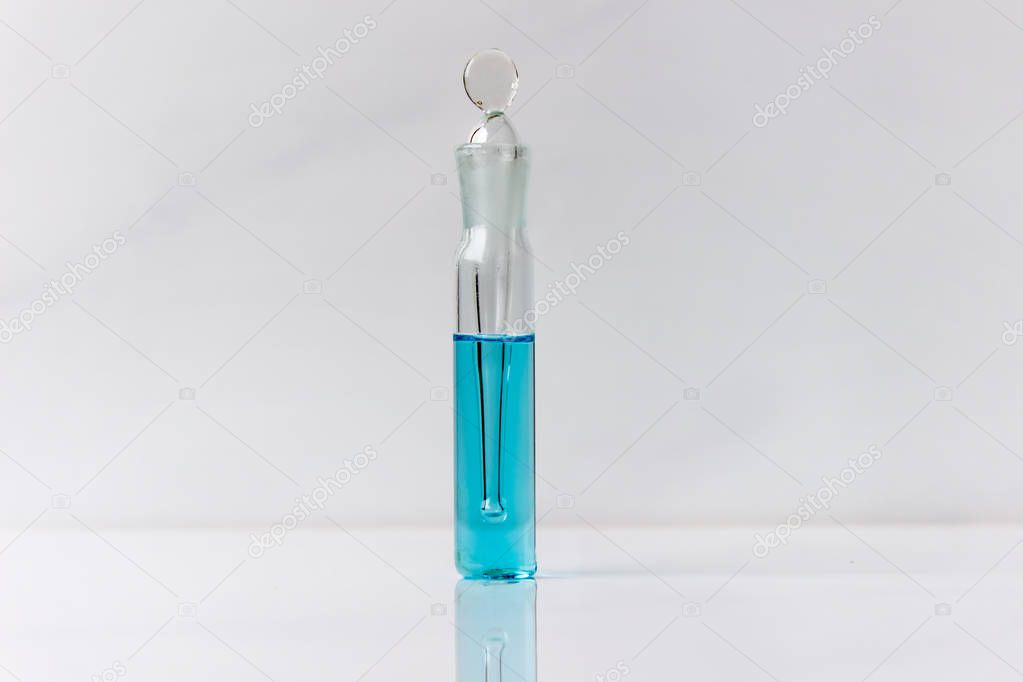 Copper sulphate solution in a tiny vessel. Blue liquid in glassware isolated on white background.