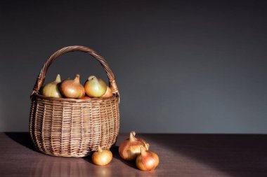 Mutfak masasının üzerinde bir sepet içinde ham altın soğan.