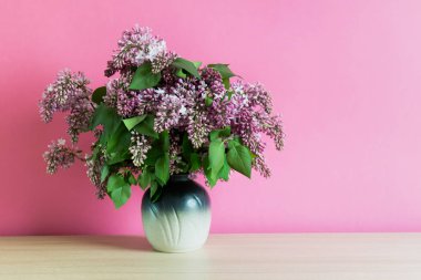 Kopya alanı ile pembe arka plan üzerinde bir vazoda eflatun çiçekler Buket. Romantik yaz leylak çiçek.