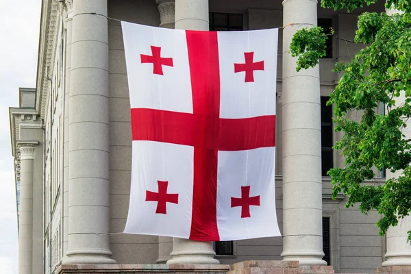 Georgian flag hanging on the facade of old building with columns.