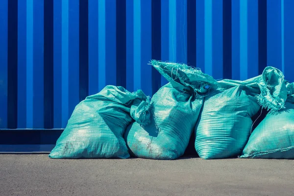 Mavi duvar yanındaki çöp kutusu arraged bina ile mavi çanta. Constration çöp bertarafı.