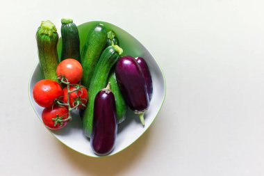 Üstten görünüm kase çeşitli sebze - patlıcan, kabak ve domates beyaz zemin üzerine dolu. Kopya boş alanı sağ ile fotoğraf.