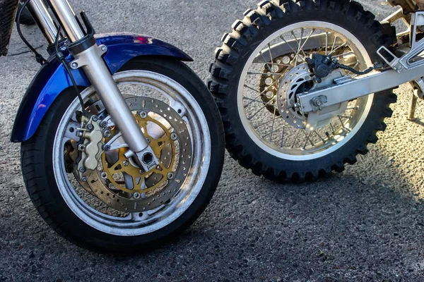 Two different motorbikes wheels next to each other.
