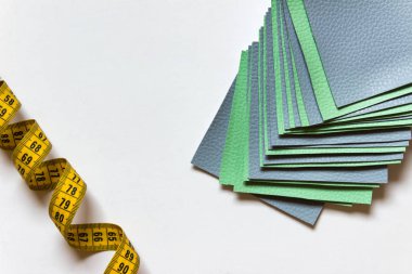 Beyaz arka plan kasette ölçme ile yeşil ve mavi renkli dikiş kumaş örnekleri.