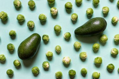 Sağlıklı sebze iki avokado ve birçok brussel lahanalar yeşil zemin üzerine desen.