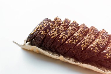 Beyaz arka plan üzerinde Kraft kağıt üzerine serpilir susam ile çavdar ekmeği dilimlenmiş.