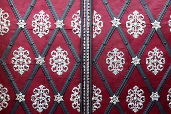 Μεσαιωνικές πόρτες με πλούσια μεταλλική διακόσμηση σε ροζ κόκκινο σούρφα — Φωτογραφία Αρχείου
