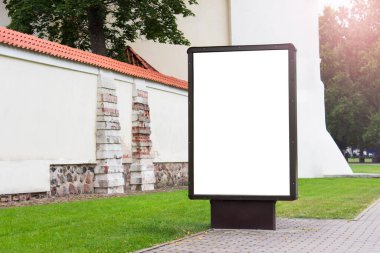 Ticari reklam panolarının dışında dikey ayakta duran, arka planında beyaz boşluk olan antik tarihi bina cephesi.