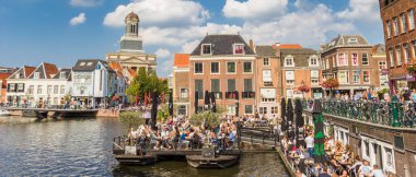 Panorama of people enjoying the sun in the center of Leiden, Holland clipart