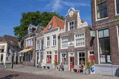 People sitting in the sun in front of a historical building in Zwolle clipart