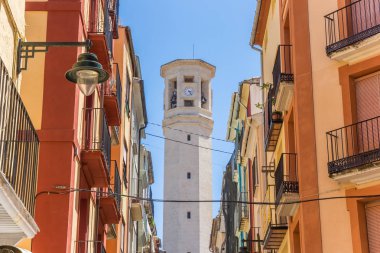 Colorful street and tower of the Sant Maure and Francesc church in Alcoy, Spain clipart