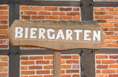 Beer garden sign in front of a traditional german half-timbered wall clipart