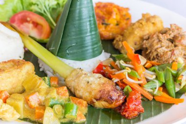Nasi Campur Bali with tempeh, chicken and vegetables, served on a banana leaf clipart