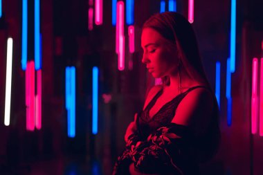 Neon tüplerin seksi iç çamaşırı ve tamamen çıplak omuz ile openned kimono bir duvara duran şehvetli genç kadın