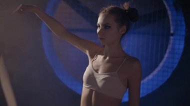 Güzel genç jimnastikçi kadın orta yakın çekim çekim bir şerit moody steampunk tarzı Gym salonunda büyük endüstriyel fan karşı karanlık bir arka plan ile eğitim yapmak. Yavaş hareket, fit422 Hq, düz