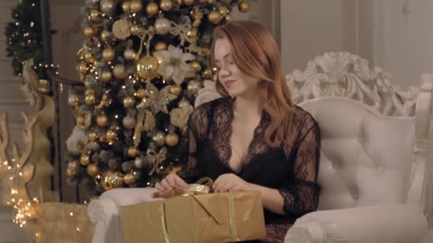 Attraktive junge Frau in transparentem Spitzenpeignoir mit ihrem Weihnachtsgeschenk — Stockvideo