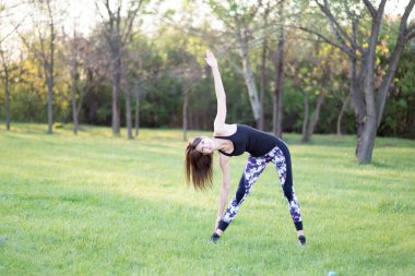 Genç bir kadın parkta egzersiz yapıyor.