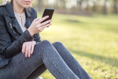 Parkta akıllı telefon kullanan kadın.