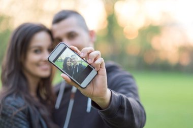 Çift akıllı telefondan selfie çekiyor.