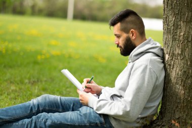Park konseptinde öğrenen yakışıklı sakallı adam.