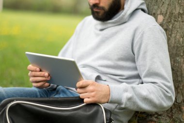 Parktaki çimlerde tabletli bir adam.