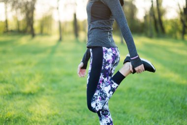 Genç bir kadın parkta egzersiz yapıyor.