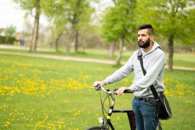 Parkta bisikleti olan genç yakışıklı adam.