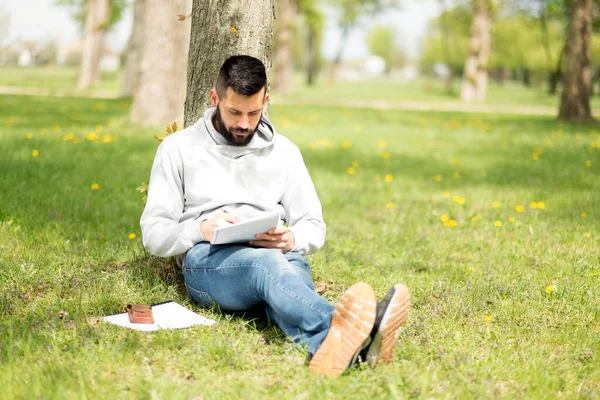 Junger Mann Sitzt Auf Gras Und Liest Buch — Stockfoto