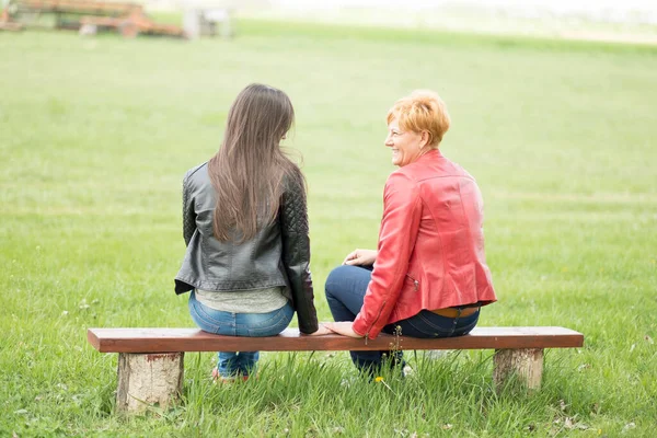 母と娘は公園のベンチに座って — ストック写真