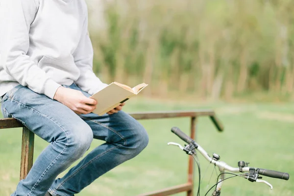 公園のベンチに座って本を読んでいる若い女性は — ストック写真