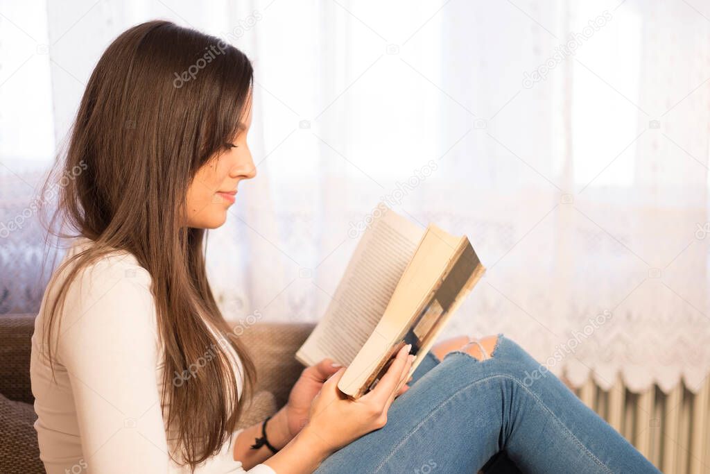 young woman reading book at home