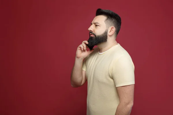 Şirin ve sakallı bir esmer adam kırmızı bir arka plan üzerinde duygusal telefonda diyor