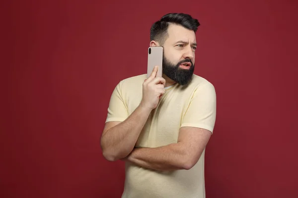 Şirin ve sakallı bir esmer adam kırmızı bir arka plan üzerinde duygusal telefonda diyor