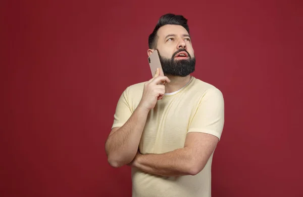 Şirin ve sakallı bir esmer adam kırmızı bir arka plan üzerinde duygusal telefonda diyor