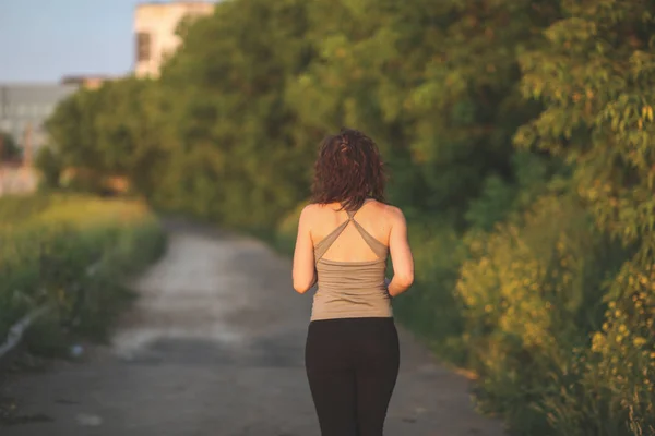 woman in sports shirt jogging in park at sunset