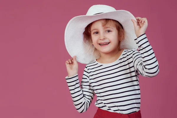 Happy little girl in white hat at pink studio background. — Stock Photo, Image