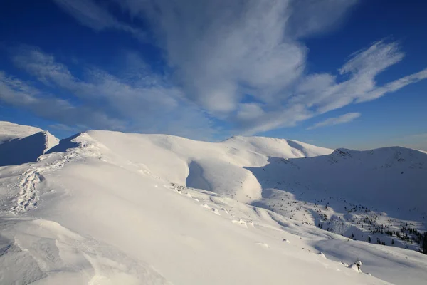 O céu azul brilhante acima das encostas cobertas de neve da montanha — Fotografia de Stock