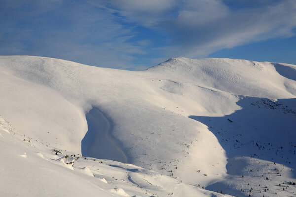 The bright blue sky above the snow-covered slopes of the mountain