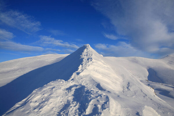 The bright blue sky above the snow-covered slopes of the mountai