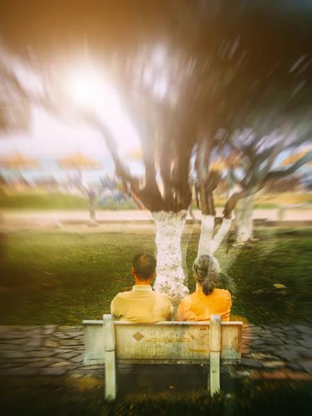 Sarı elbiseli bir çift Vietnam 'daki şehir parkındaki ağaçlara bakıyor.